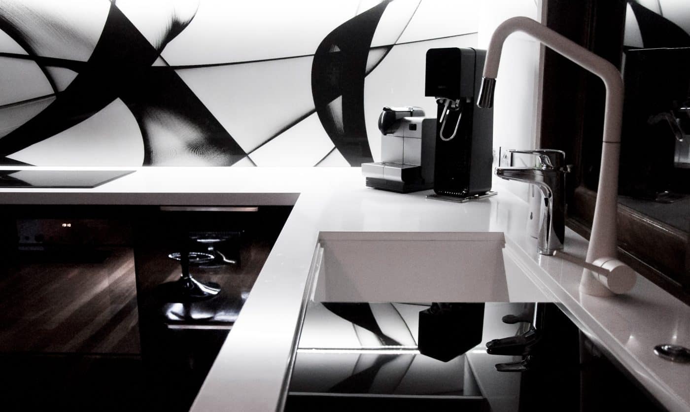 Improve Water Quality in your New Apartment 6 A modern kitchen in a new apartment with a black and white color scheme. It features a sink, a coffee machine to start your morning right, abstract wall decor, and enhanced systems to improve water quality.