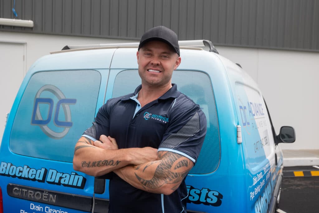 Water supply to fridge 3 A man wearing a cap and company uniform stands in front of a branded van with his arms crossed, smiling. The van displays 'DC' logos and text related to drainage and plumbing services.