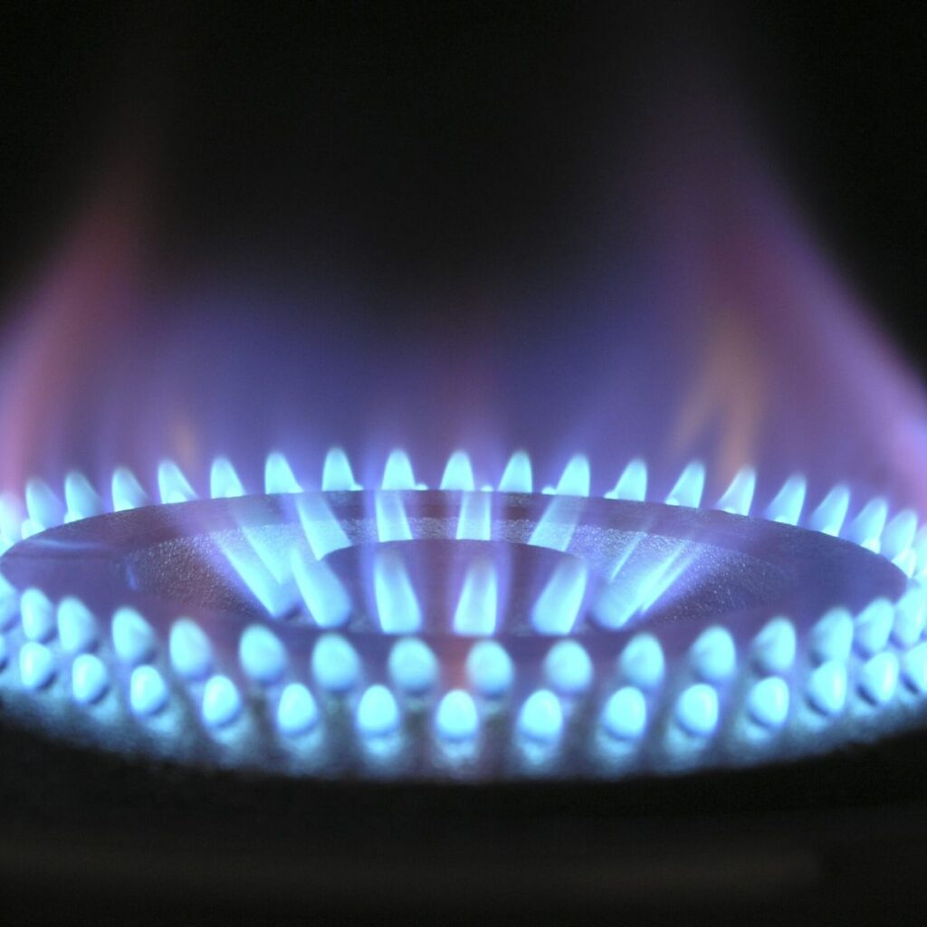 Residential Plumbing 1 Close-up of a blue gas flame on a stove burner, glowing evenly around the circle with a soft purple hue at the tips, set against a dark background—a testament to expert plumbing services ensuring flawless performance.